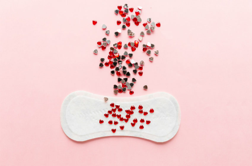 Menstruasjonsbind og røde perler. Foto.