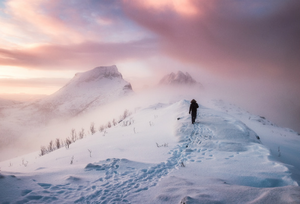 Person som går på et snødekket fjell. Foto. 