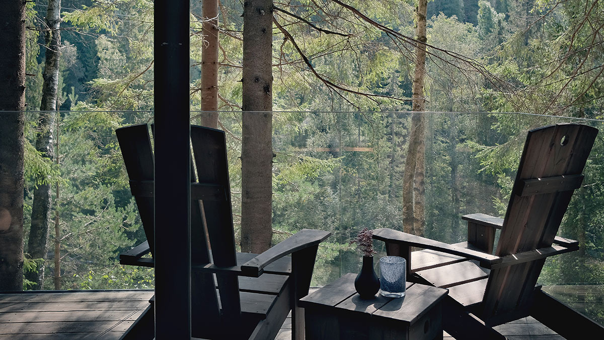 Terrasse på glasshytte i skogen. Foto.