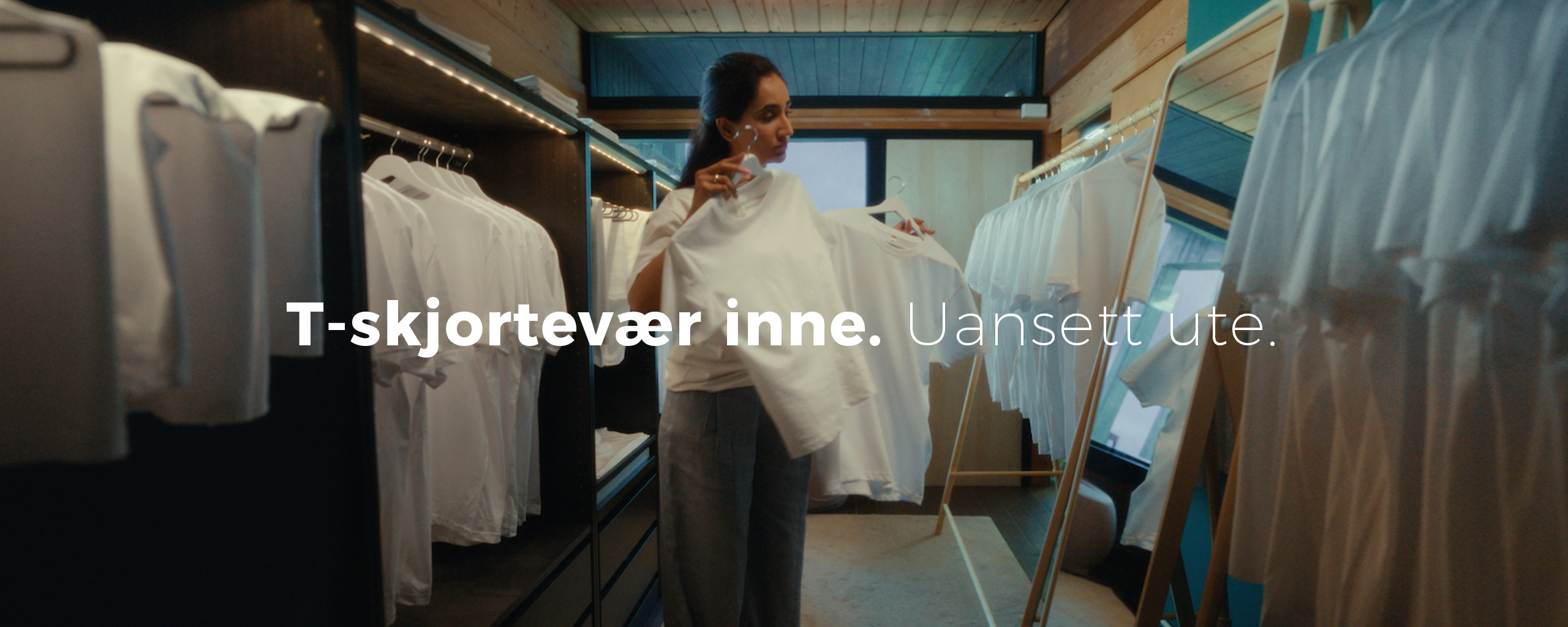 Jente i walk in-closet, med masse hvite t-Skjorter. Foto.